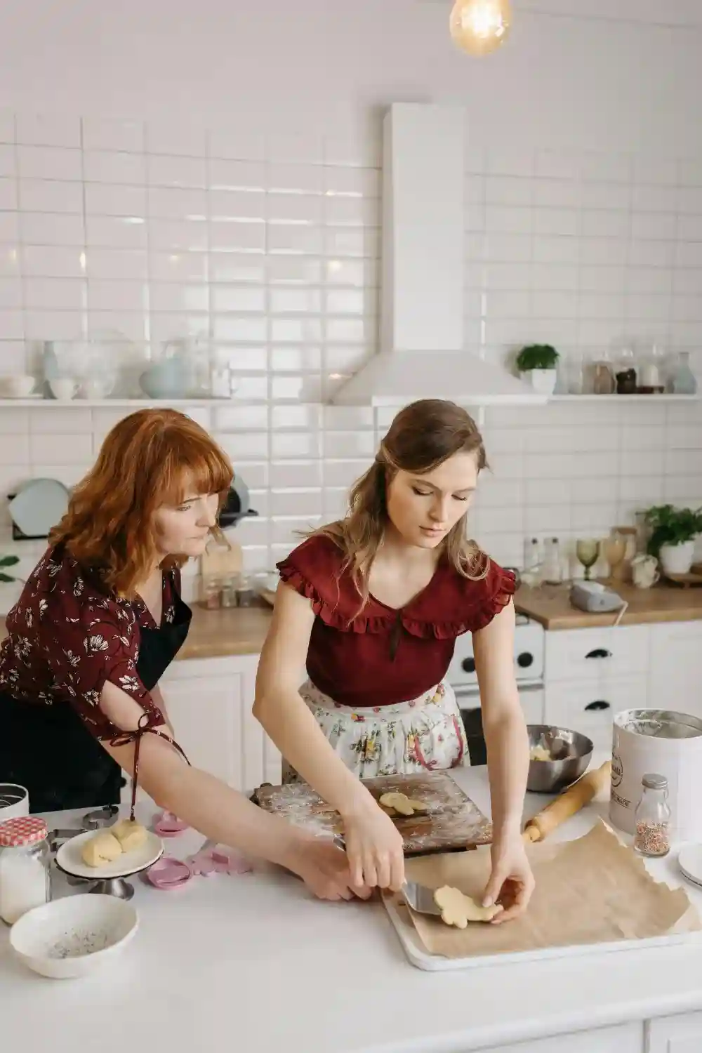 Ashley Wilson and Amanda Valley laughing while cooking together in the kitchen