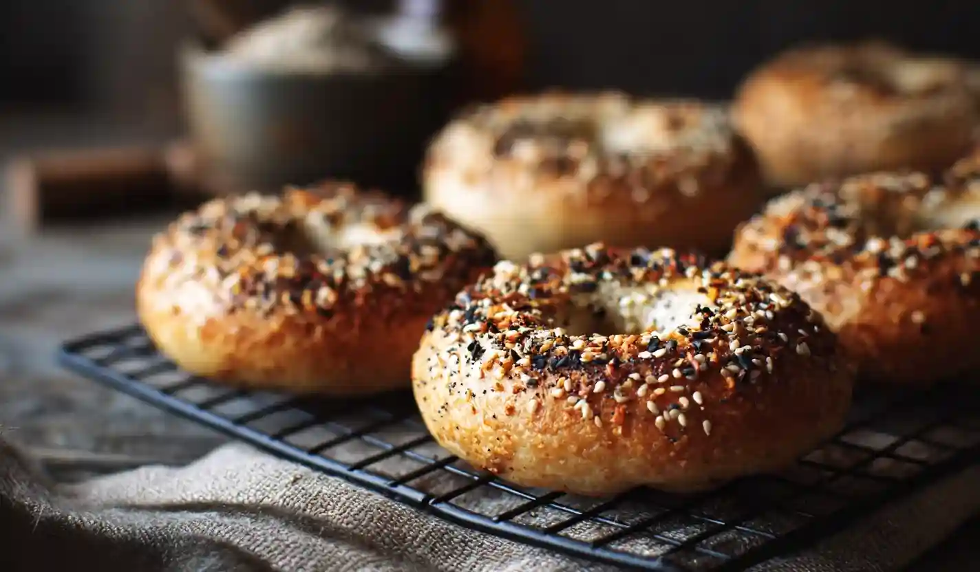 Golden gluten-free bagels with seeds on cooling rack