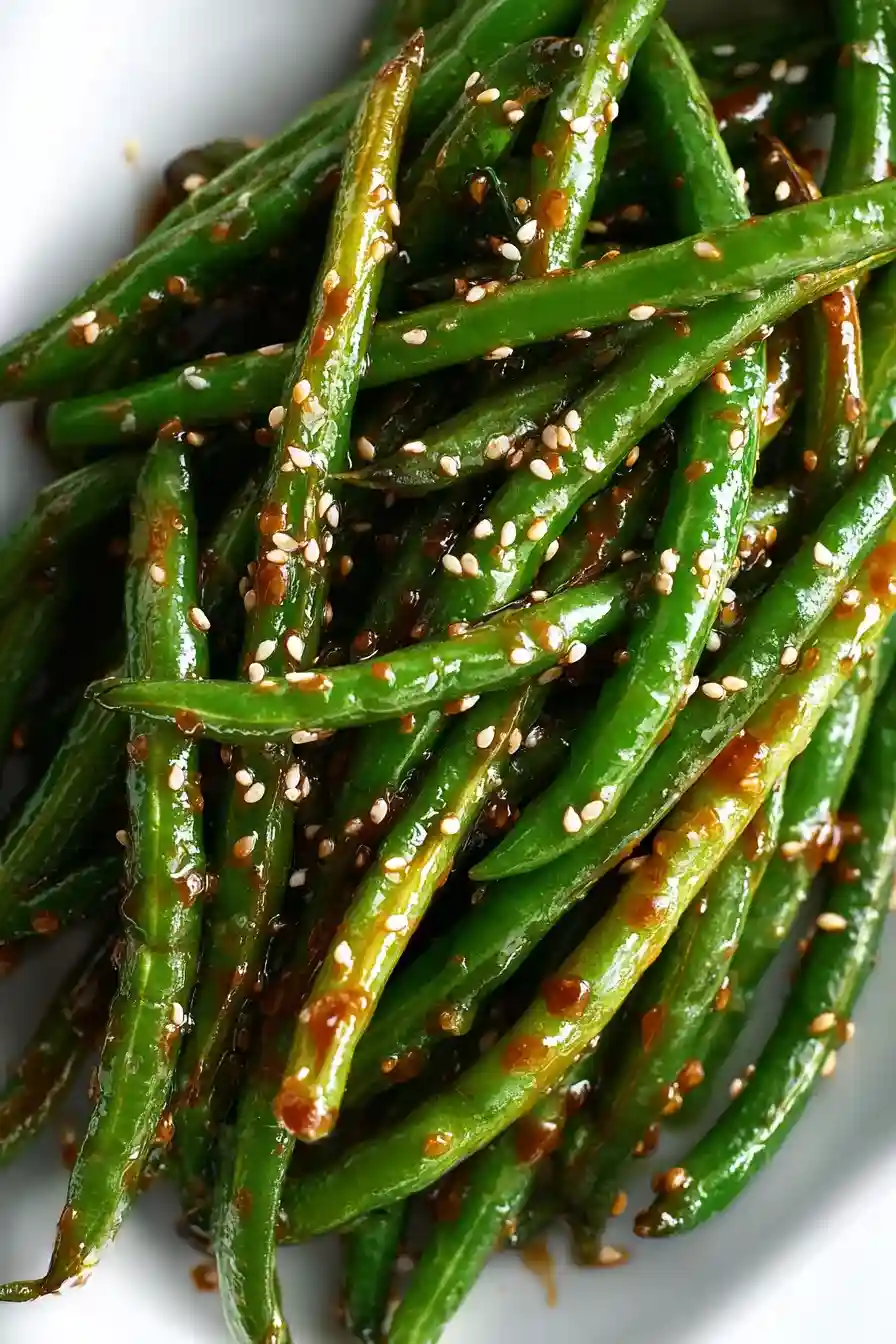 Close-up of miso green beans served in a modern white dish with glossy miso glaze and toasted sesame seeds.